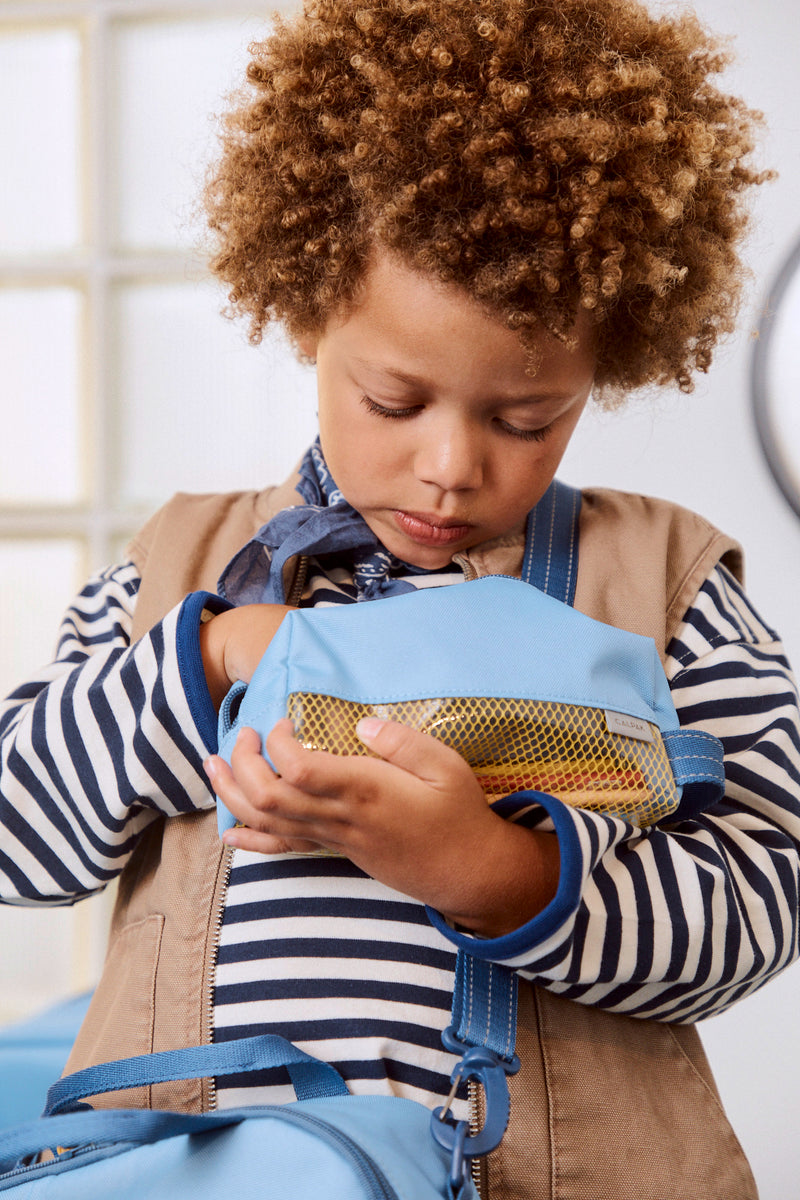 Child with a blue CALPAK Kids Pencil Case indoors
