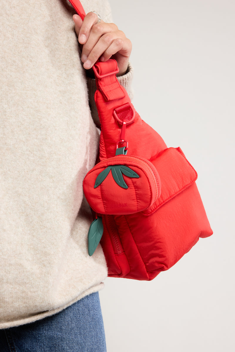Woman wearing a bag with CALPAK Tomato Zip Bag Charm with green leaf zipper and red clip