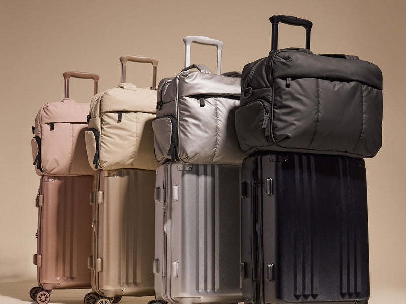 CALPAK collection of Ambeur suitcases and Luka Duffel bags in various colors on a beige background
