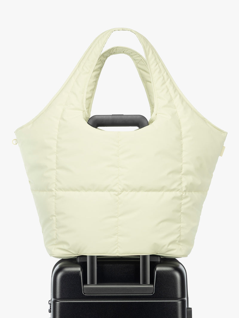 Luggage trolley sleeve of the CALPAK Luka Everything Laptop Tote in light green Celadon with shoulder strap on a white background
