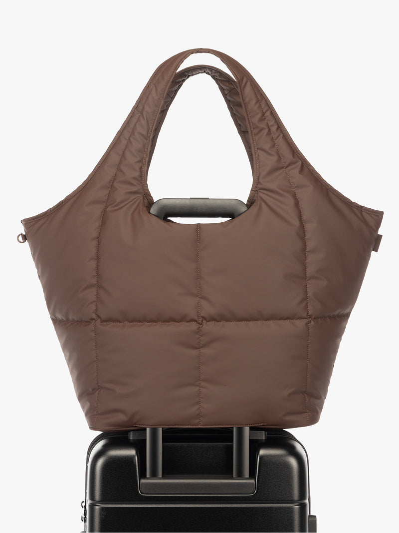 Luggage trolley sleeve of the CALPAK Luka Everything Laptop tote in brown Walnut with shoulder strap on a white background