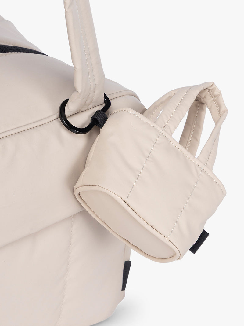 CALPAK Luka Tote Zip Bag Charm in off-white Oatmeal with carabiner attached to a bag