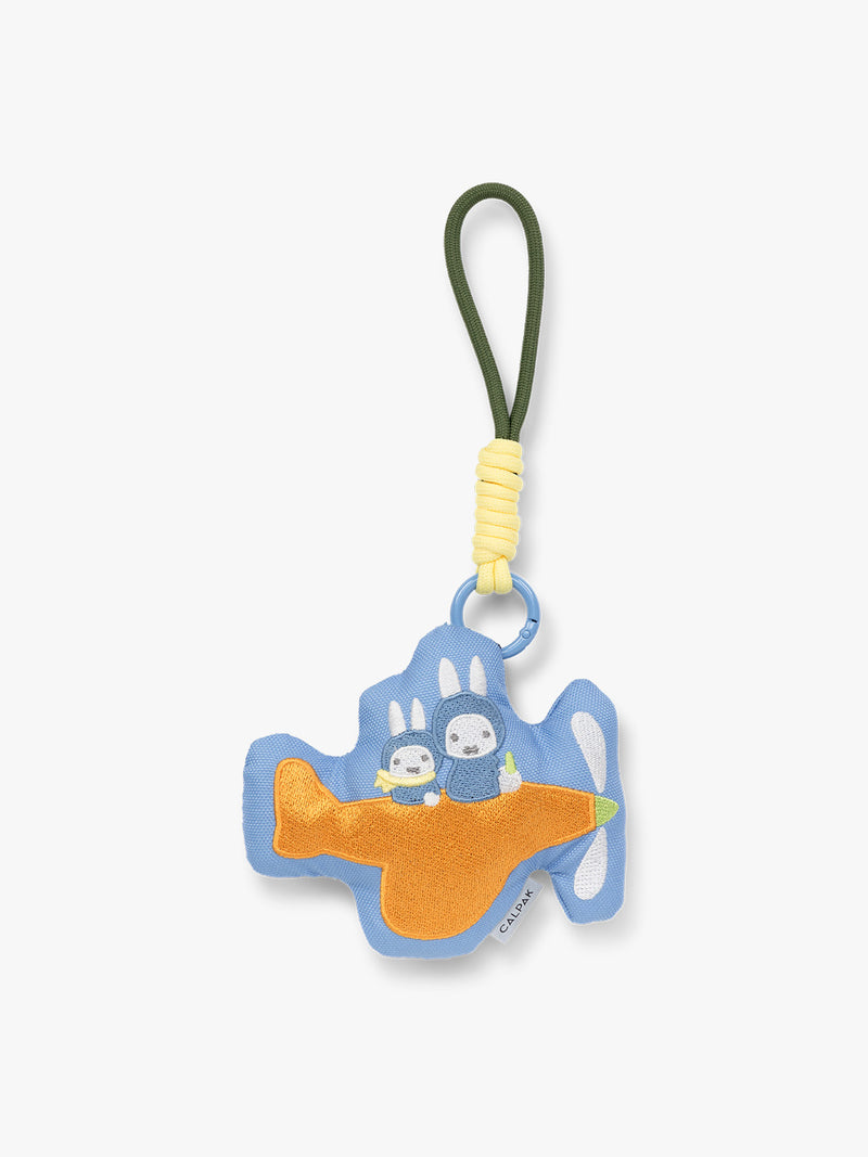 Plush Miffy x CALPAK Pluffy Bag Charm keychain with a blue border and Miffys holding a carrot on an orange airplane with a white background