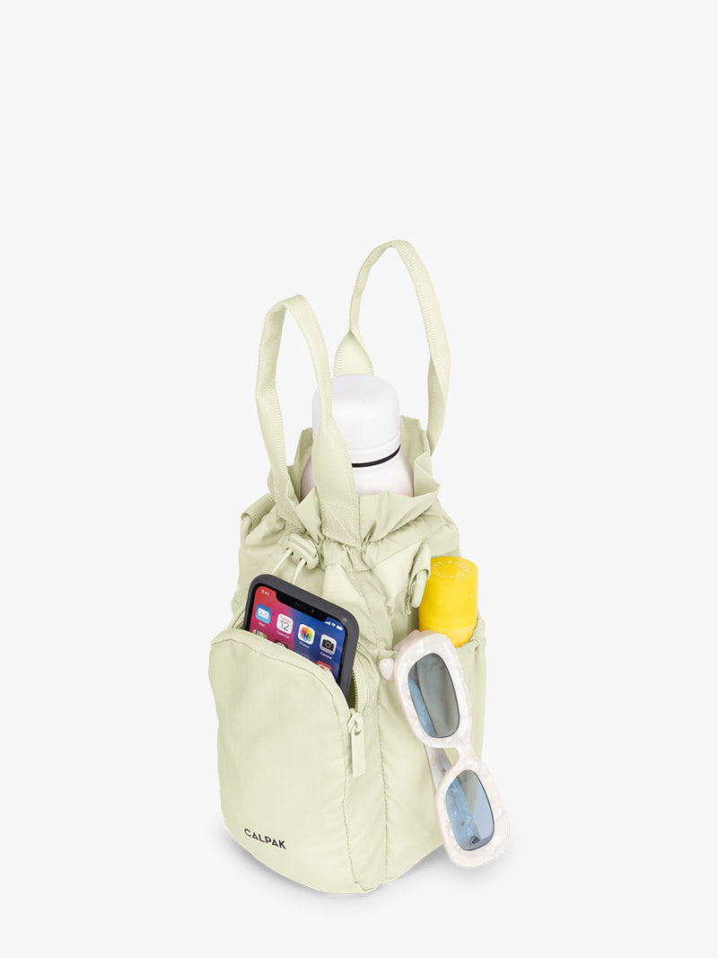 Water bottle and items inside the CALPAK Water Bottle Holder in light green Celadon