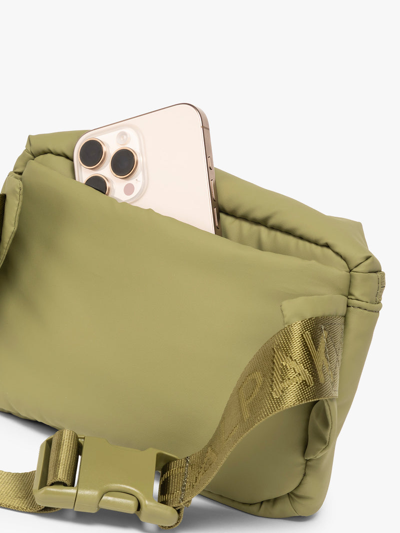 Phone in back pocket of CALPAK Luka Mini Belt Bag in dark green Pistachio on white background