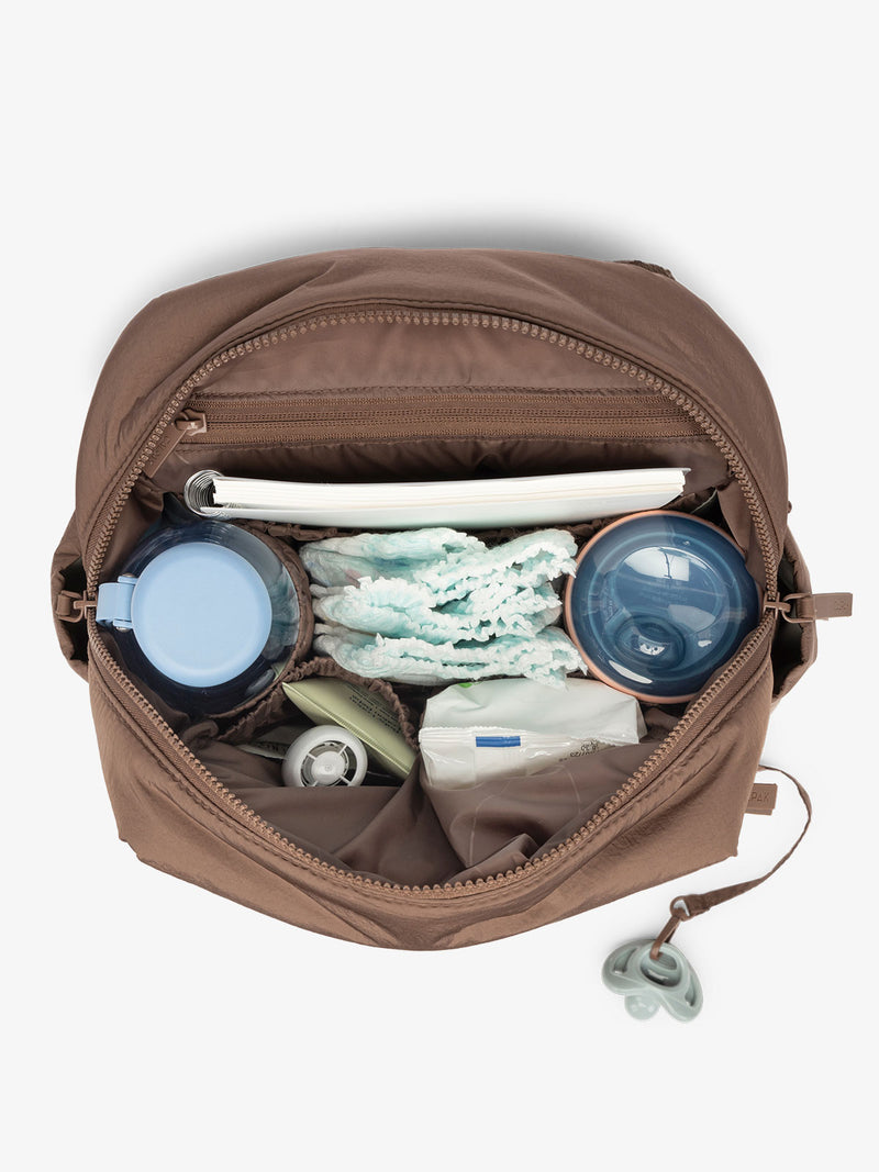 Inside view with baby items inside the CALPAK Mini Diaper Backpack in brown Hazelnut on a white background