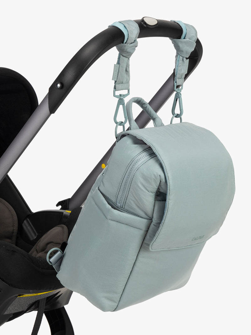 CALPAK Convertible Mini Diaper Backpack in light blue Bluebell hanging on a stroller with stroller straps