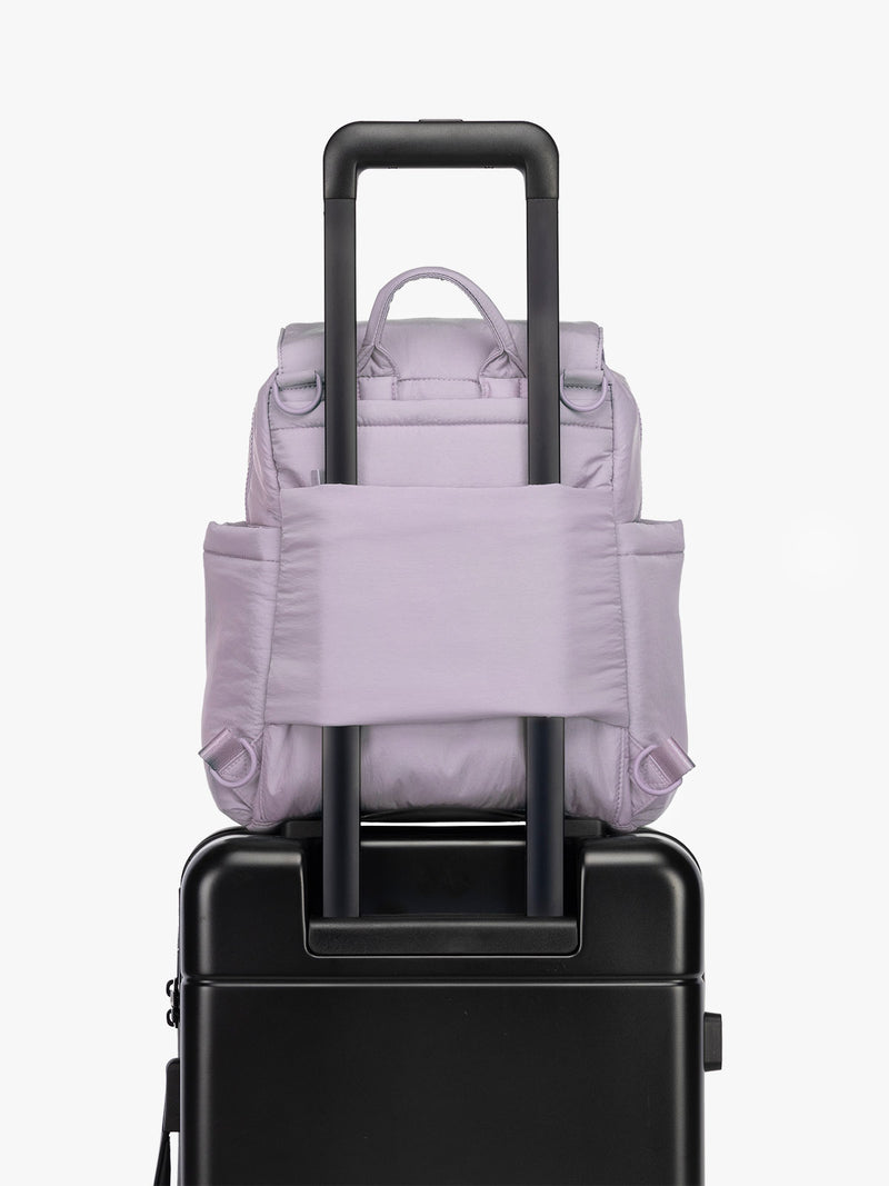 CALPAK Convertible Mini Diaper Backpack in lavender purple on luggage with trolley sleeve