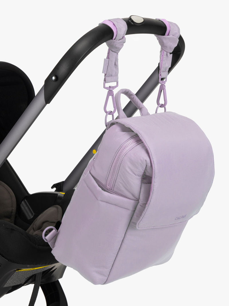 CALPAK Convertible Mini Diaper Backpack in lavender purple hanging on stroller with stroller straps
