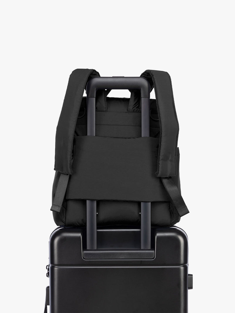 Luggage trolley sleeve of the CALPAK Mini Diaper Backpack in Black on a white background