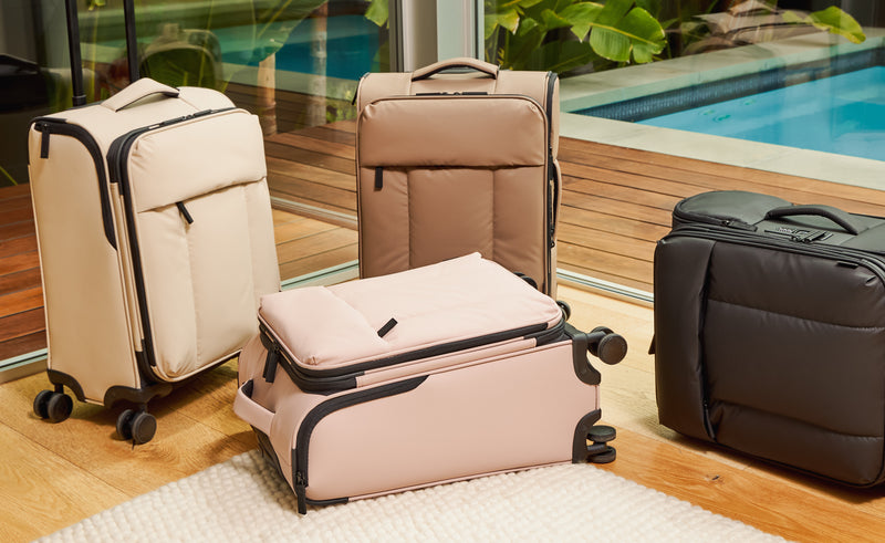 CALPAK Luka Soft-Sided Carry-On Luggages in living room in oatmeal, chocolate, rose quartz and matte black