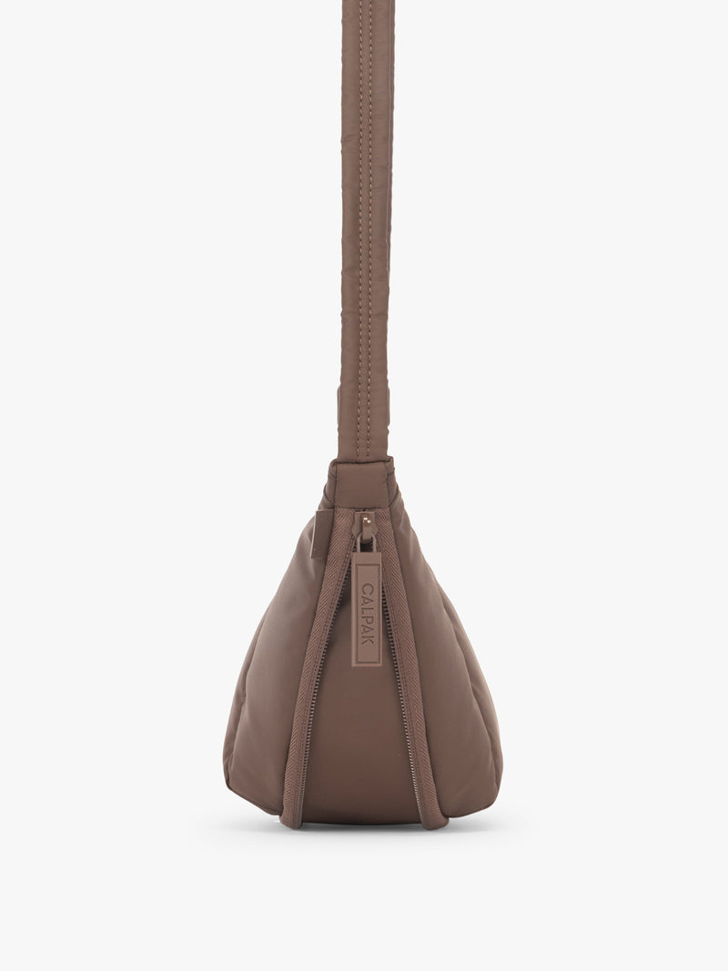 Side view showing function of 2" expandable feature of the CALPAK Luka Crescent Tote bag in brown Walnut with shoulder strap and bag is expandable up to 2"
