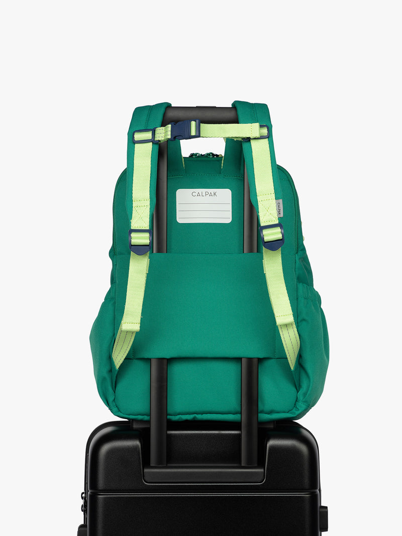 Back luggage trolley sleeve and name tag of green CALPAK Kids Large Backpack with lime green accents on a white background