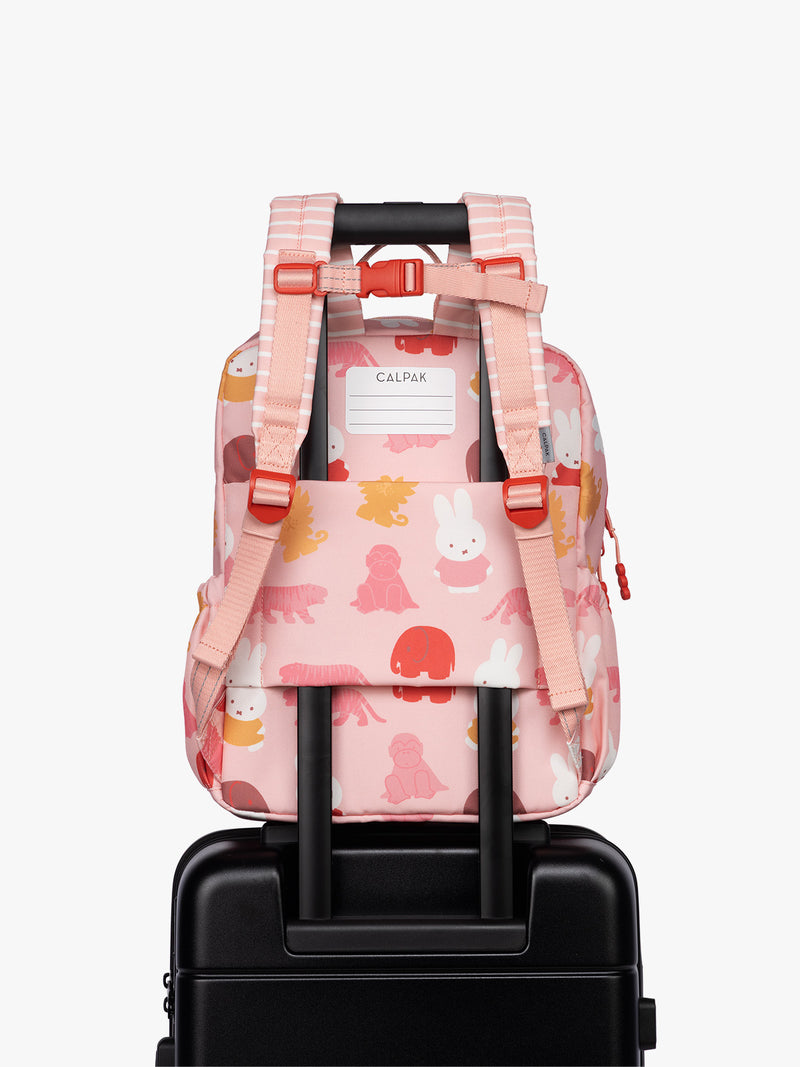 Back luggage trolley sleeve of CALPAK Kids Medium Backpack with Miffy and pink colorful animal pattern on a white background