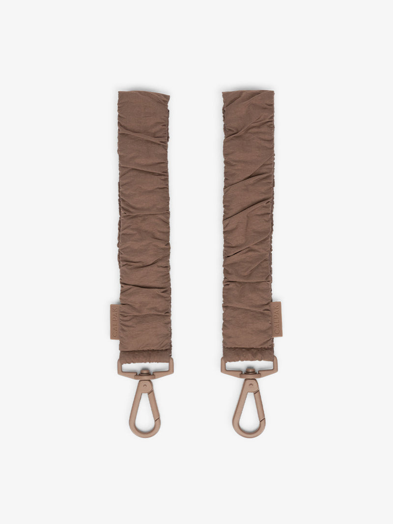A set of two stroller straps for a diaper bag in hazelnut color, featuring durable metal clips and adjustable straps. The straps are designed to attach a diaper bag securely to a stroller