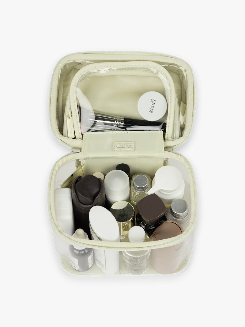 Toiletry items inside the CALPAK Clear Train Case in light green Celadon