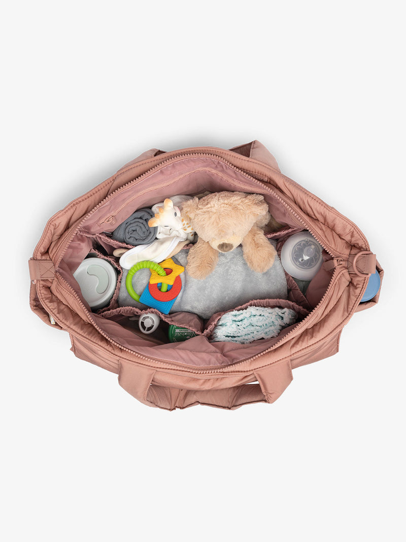 An overhead shot of the inside of a pink diaper tote bag. Its multiple compartments and large size are on show