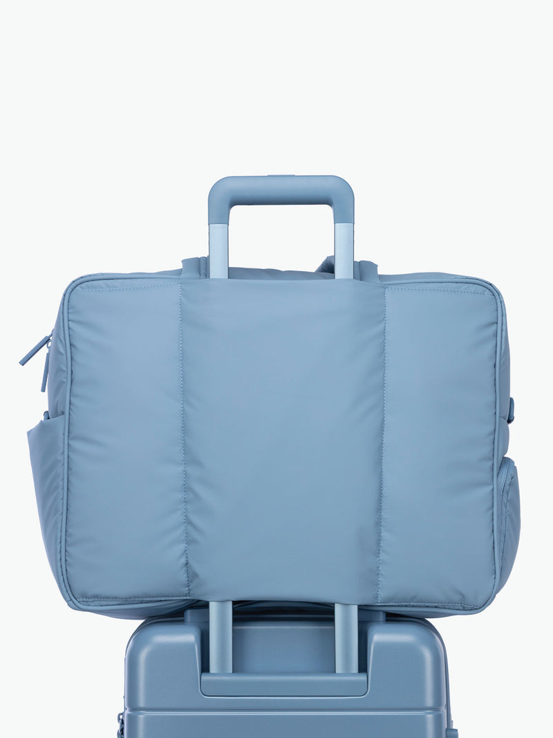 CALPAK Luka Large duffel bag in French Blue attached to suitcase using trolley sleeve for airport travel