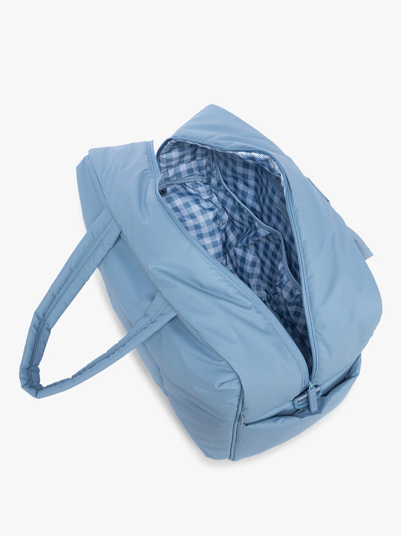 Interior of CALPAK Luka Large duffel bag in French Blue showing spacious main compartment and organization pockets and french blue gingham print inside