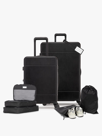 Opened CALPAK Hue Starter Bundle in Black that comes with Large and Carry On Luggage, Luggage Tag, Two Black Pouches, and Three Black Packing Cubes shown on a white background; LHU8000-BLACK view 1
