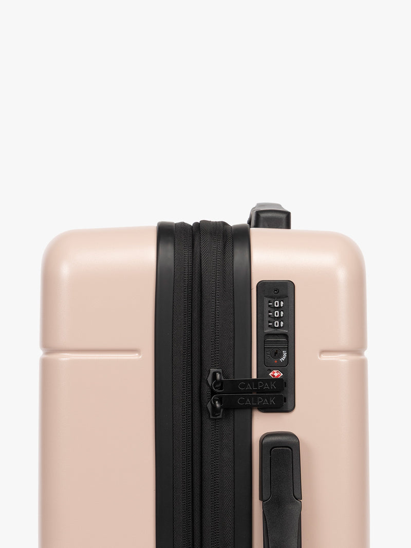 TSA-approved lock on the CALPAK Hue Starter Bundle in light pink Rose Quartz that comes with Large and Carry On Luggage with op handle on a white background