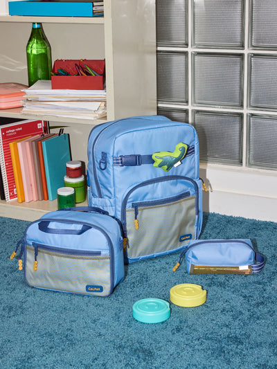 CALPAK Kids Collection Large Kids Backpack Bundle in Blue that includes Kids Lunch Bag, Kids Pencil Case, Rainbow Pluffy Bag Charm, and Set of 2 Ice Packs in a kid's room; BCKL5000-BLUE view 2
