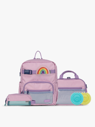 CALPAK Kids Collection Small Kids Backpack Bundle in pink lavender Orchid Pink that includes Kids Lunch Bag, Kids Pencil Case, Rainbow Pluffy Bag Charm, and Set of 2 Ice Packs in a kid's room; BCKS5000-ORCHID-PINK view 1