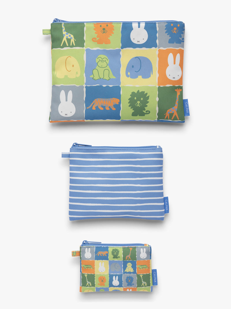 Flat-lay of a set of blue, white, green, and yellow colorful children's pouches with Miffy and animal patterns for the CALPAK Compakt Zip Pouch Set on a white background