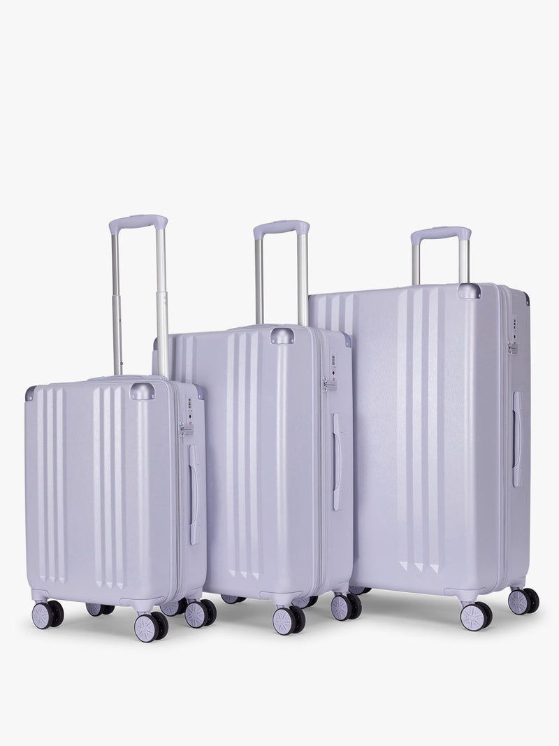 CALPAK Ambeur three piece luggage set in carry on, medium, and large sizes in light purple lavender with handles and spinner wheels on a white background