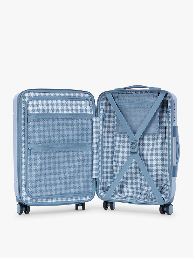 Opened view with CALPAK Hue Carry On Luggage in light blue French Blue and blue and white gingham interior