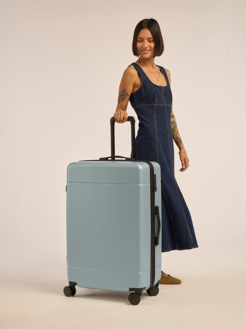 Model with CALPAK Hue Large Luggage in blue Bluebell; LHU1028-BLUEBELL