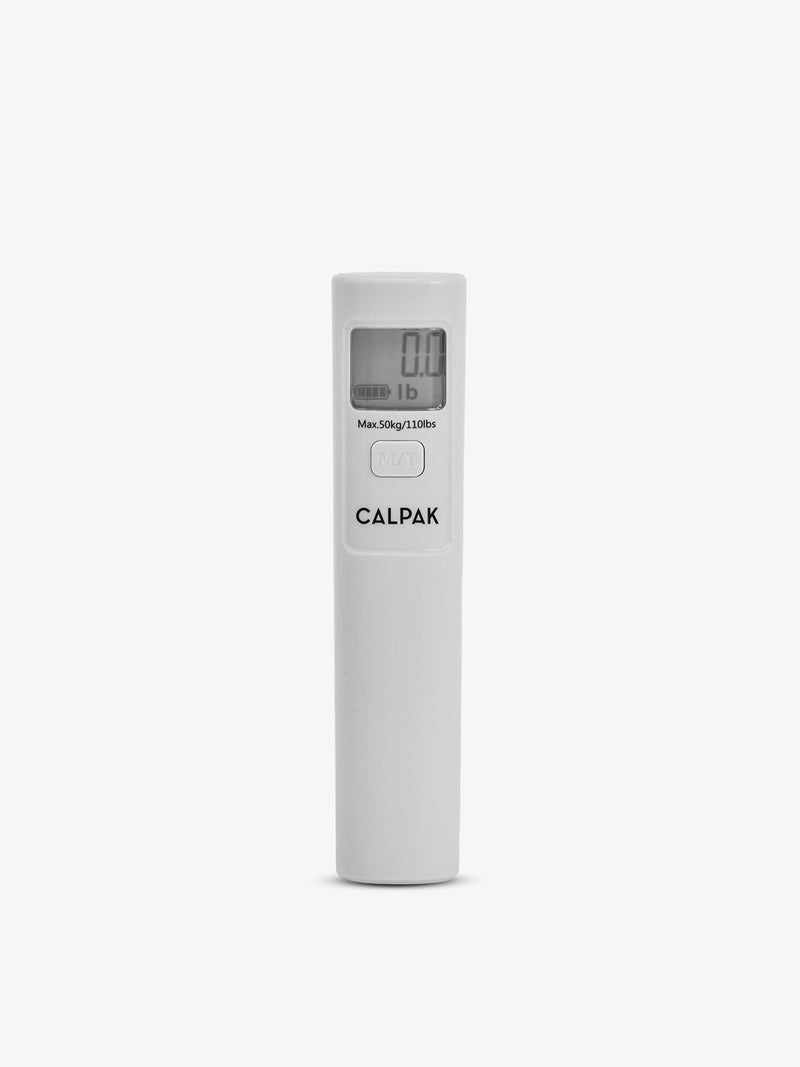 The Battery-Free Luggage Scale held in hand over a suitcase, featuring a simple strap and mechanical dial display.