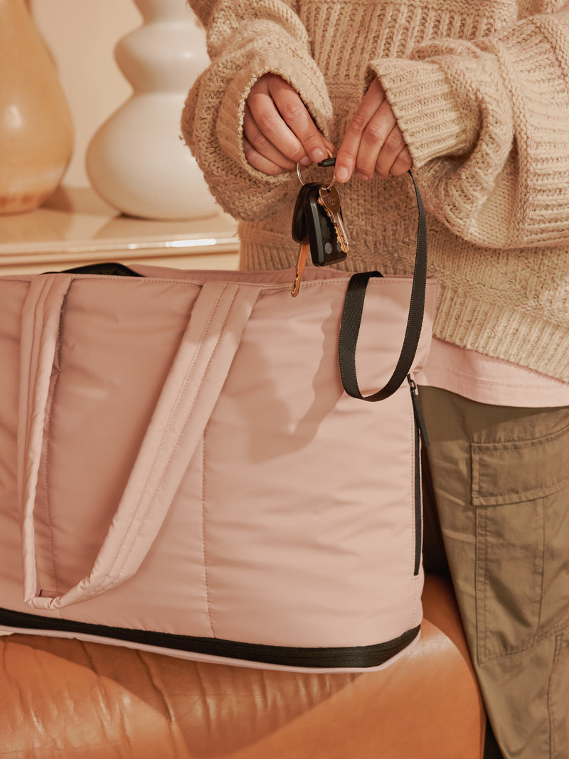 Model displaying key clip of CALPAK Luka Expandable Laptop Tote in Rose Quartz