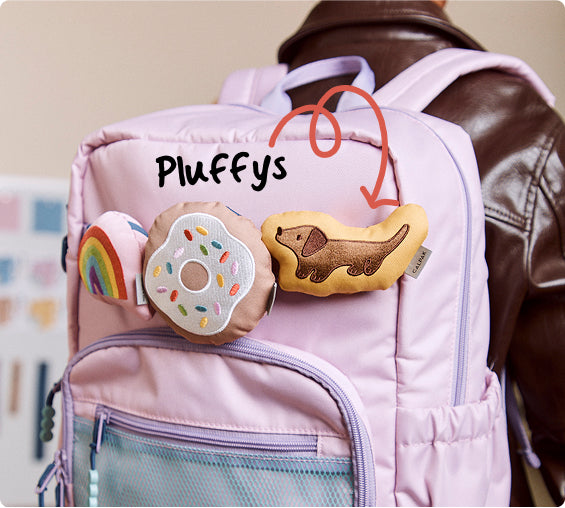 Pink CALPAK Kids backpack with plush toys shaped like a donut and a rainbow, and a dog, with 'Pluffy's' text.