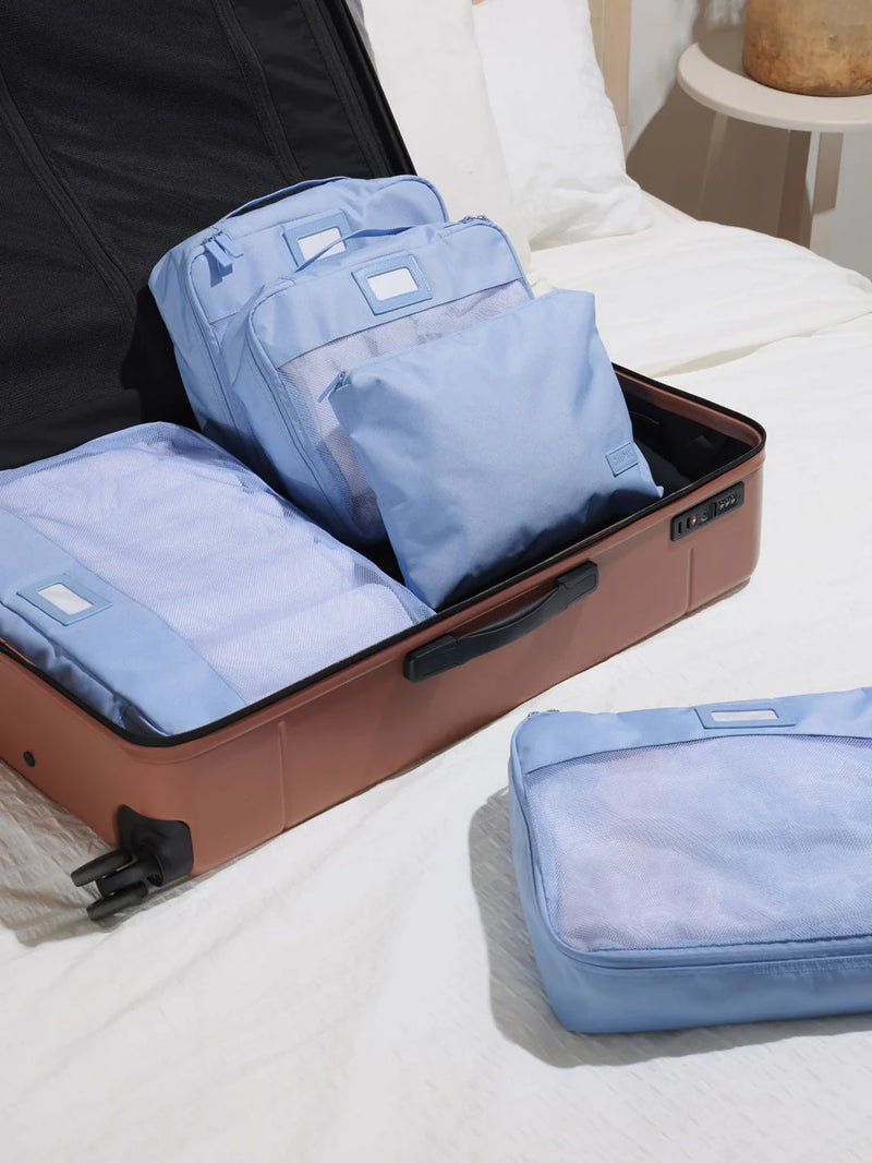 CALPAK 5-Piece Packing Cubes Set in Sky being packed inside luggage