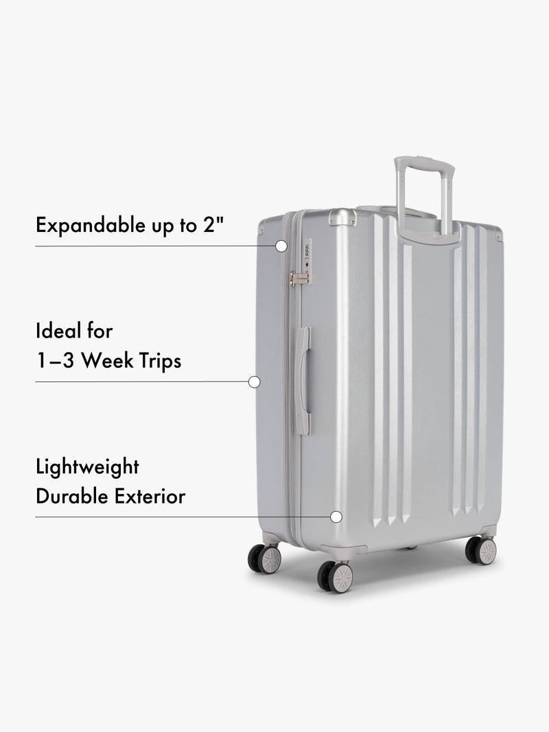 CALPAK large silver suitcase with text highlighting features on a white background
