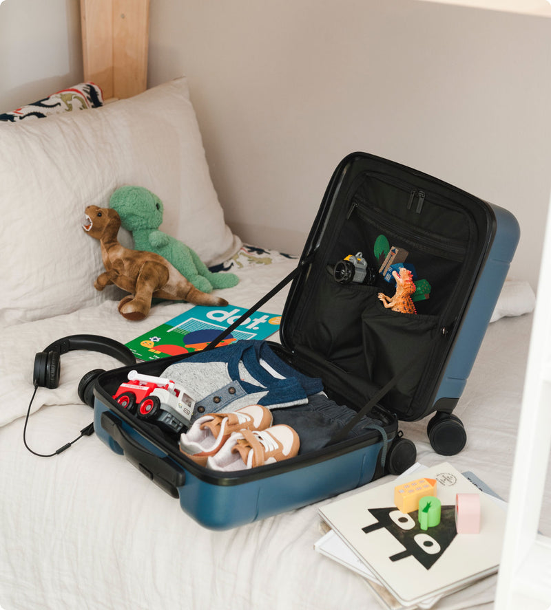 CALPAK blue Hue mini carry-on luggage packed with kids clothes and toys 