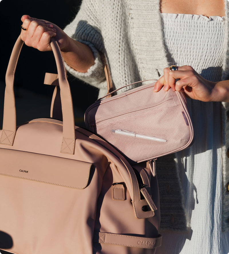 Model packing pink CALPAK tech organizer into pink Hue Duffel Bag 