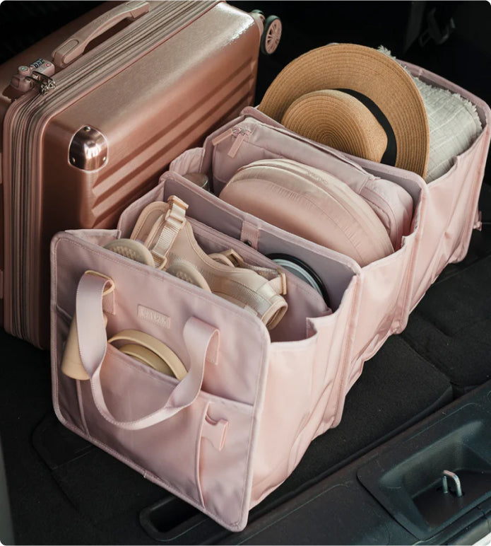 CALPAK car organizer in pink packed in the trunk of a car with pink ambeur carry-on suitcase