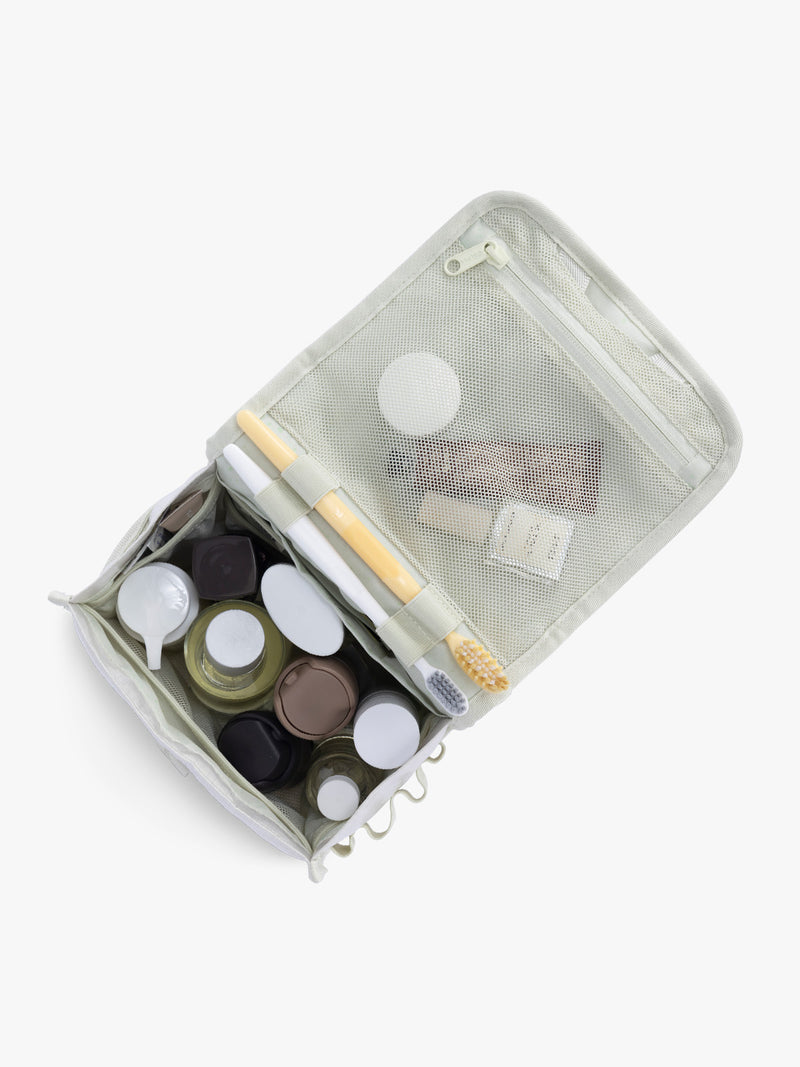 Toiletry items in CALPAK Terra Hanging Toiletry Bag in shiny white Moonbeam with front buckle