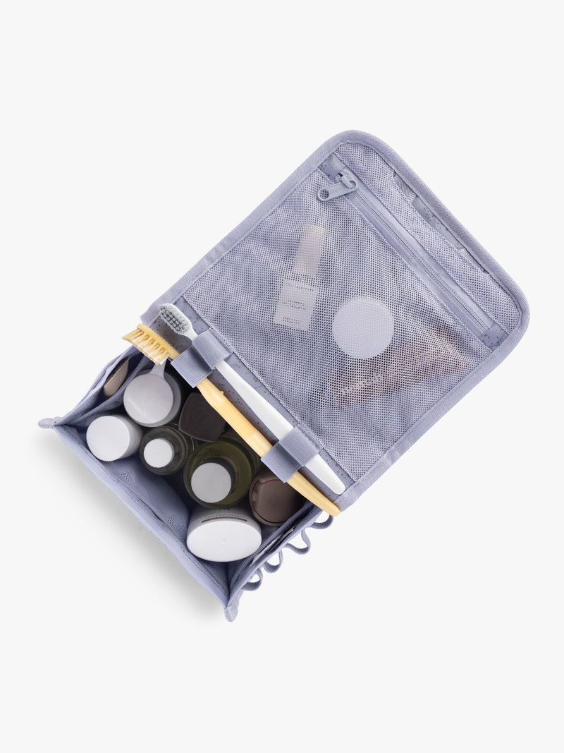 Toiletry items into CALPAK Terra Hanging Toiletry Bag in light purple Sea Glass with front buckle