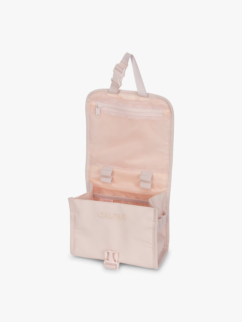 Opened CALPAK Terra Hanging Toiletry Bag in light pink Shell Pink with front buckle