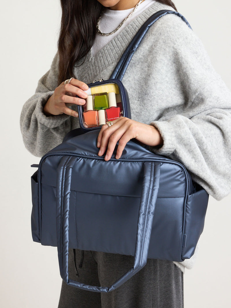 Person holding the CALPAK Clear Cosmetic Case in dark blue Metallic Indigo