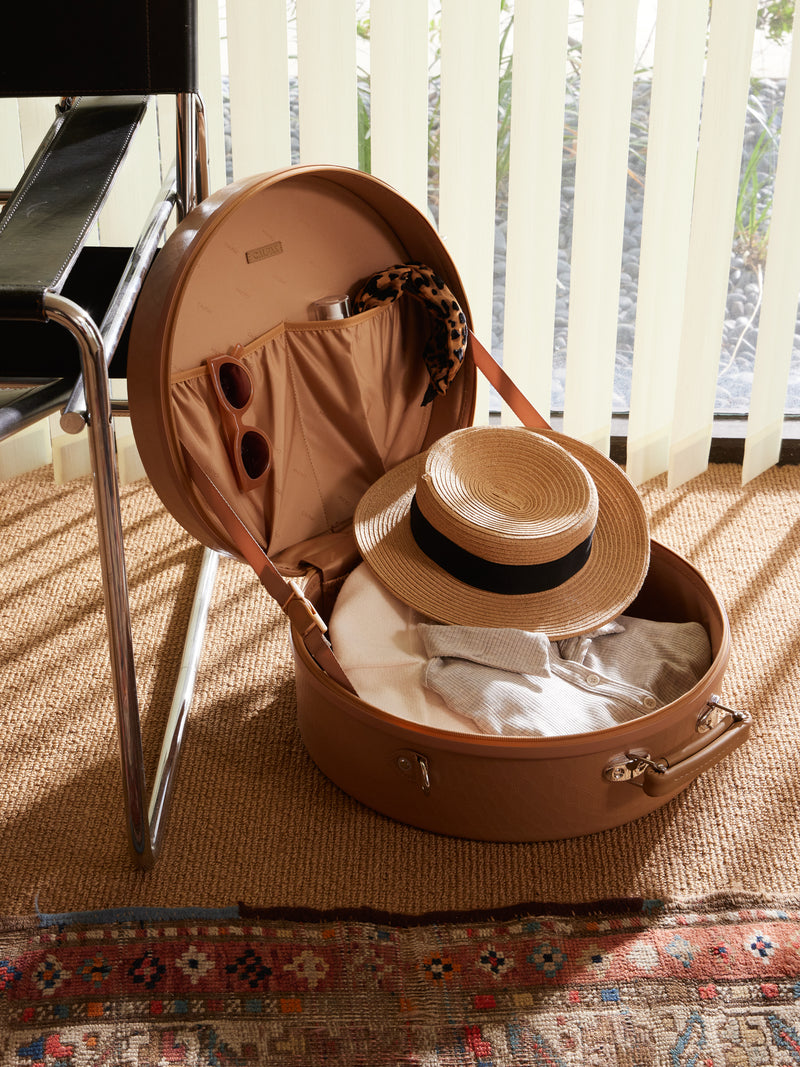 CALPAK TRNK Medium Hat Box in Almond brown filled with clothes, beach hat, sunglasses and accessories