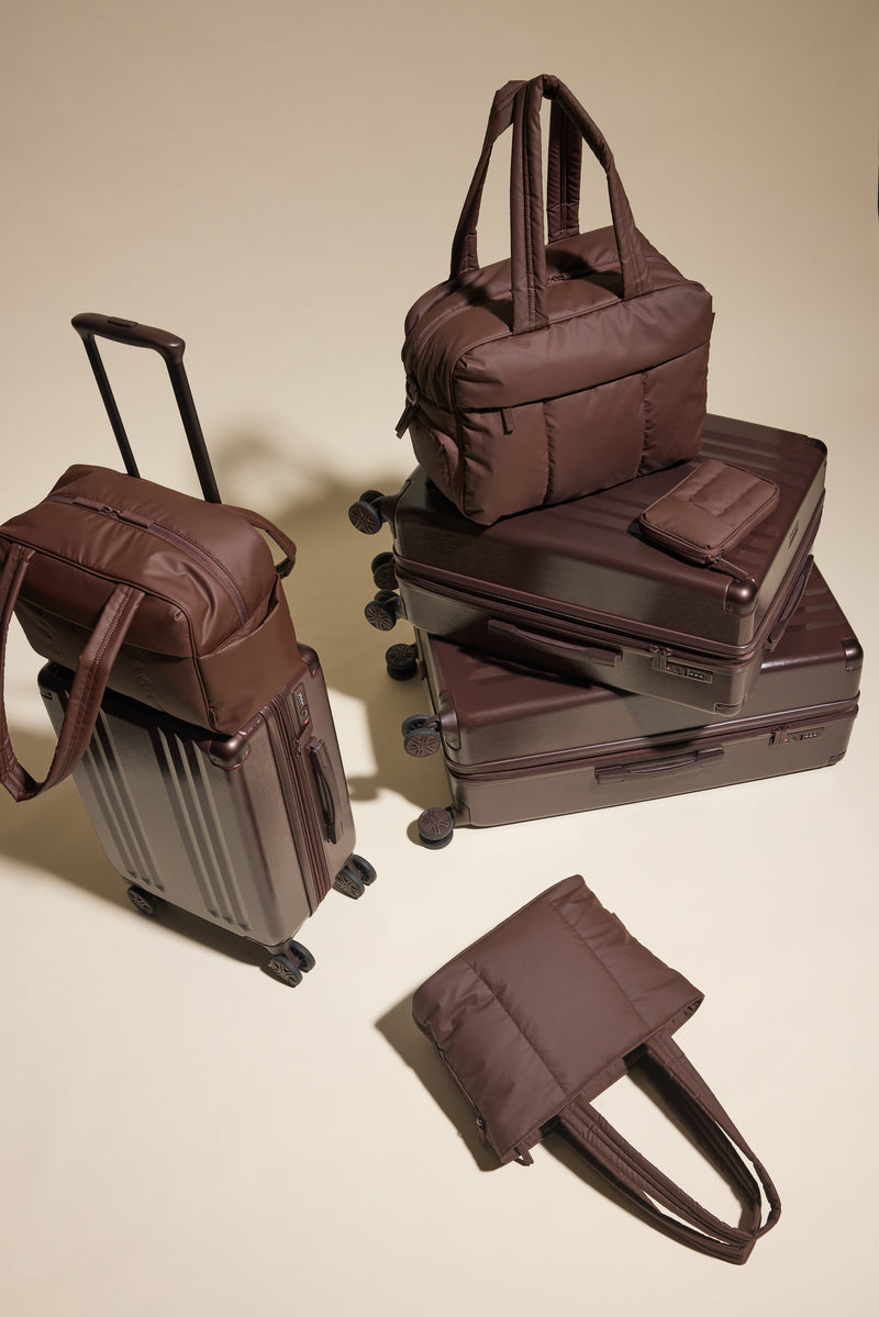 Set of brown CALPAK suitcases and bags on a beige background