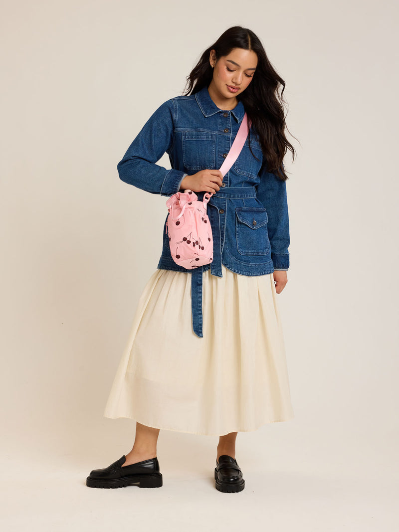 Model holding CALPAK Water Bottle Holder in Oatmeal Chery in pink with cherry pattern