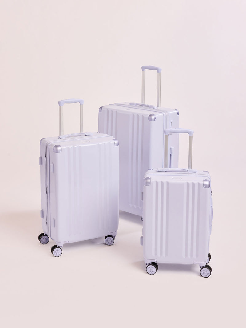 CALPAK Ambeur three piece luggage set in carry on, medium, and large sizes in light purple lavender with handles and spinner wheels on a white background