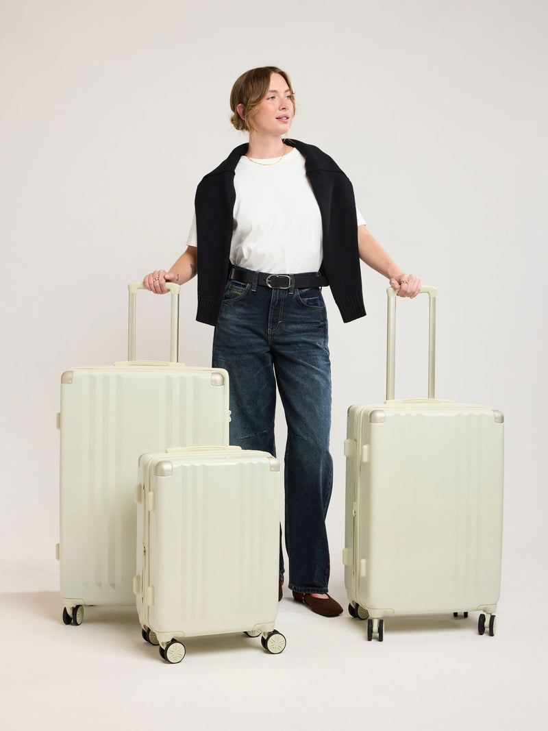 Woman wirh CALPAK Ambeur 3 piece Luggage Set in light green Celadon with sizes of Carry On, Medium, and Large