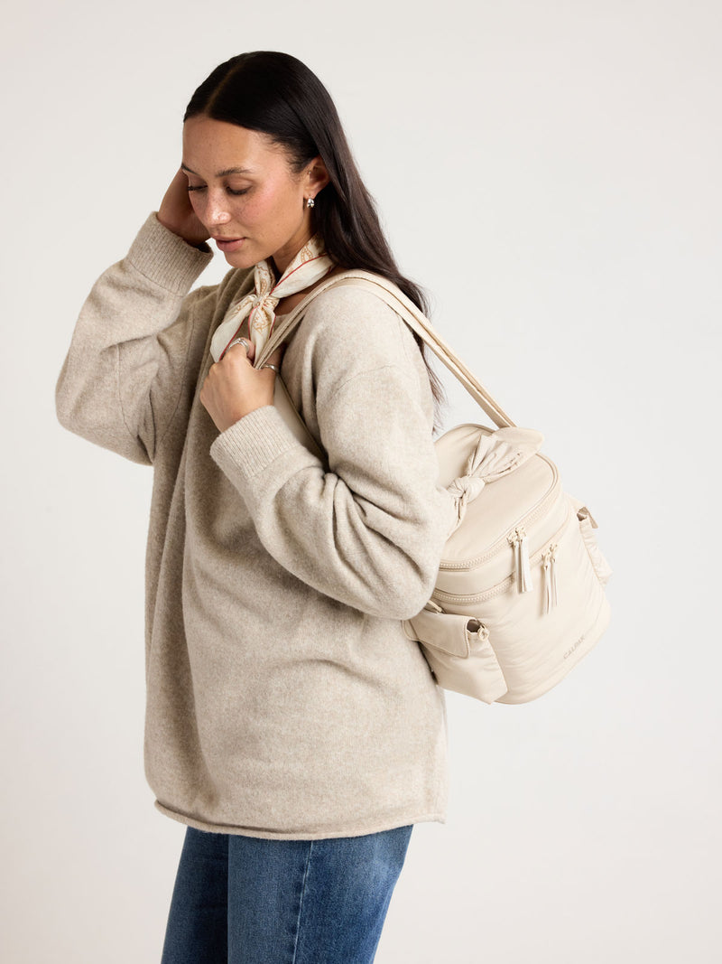 Woman wearing CALPAK Insulated Baby Bottle Bag in beige Oatmeal