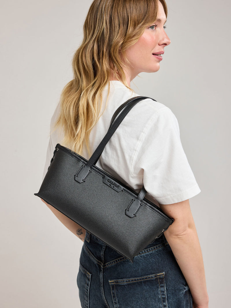Woman wearing CALPAK Colette Canvas Shoulder Tote in Black canvas material